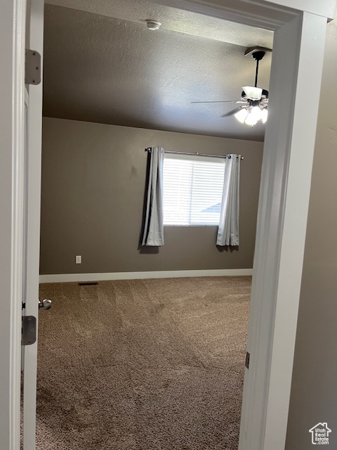 Carpeted spare room with ceiling fan and a textured ceiling