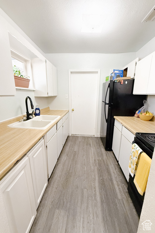 Kitchen with light wood-style floors, light countertops, white cabinetry, and electric range