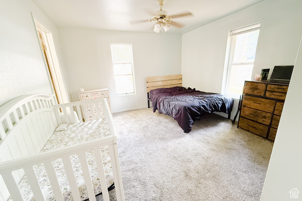 Carpeted bedroom with a ceiling fan