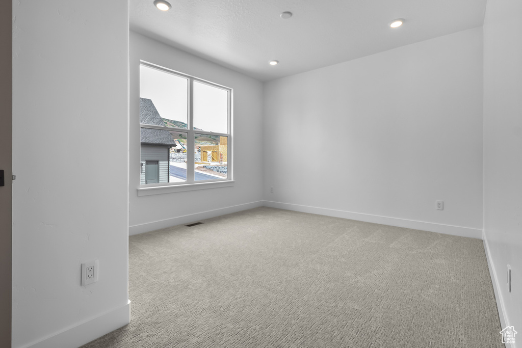 Empty room with light colored carpet and recessed lighting