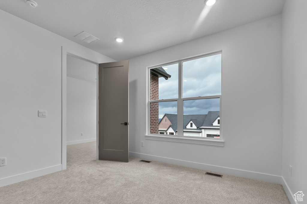 Carpeted empty room featuring healthy amount of natural light, recessed lighting, and a smoke detector
