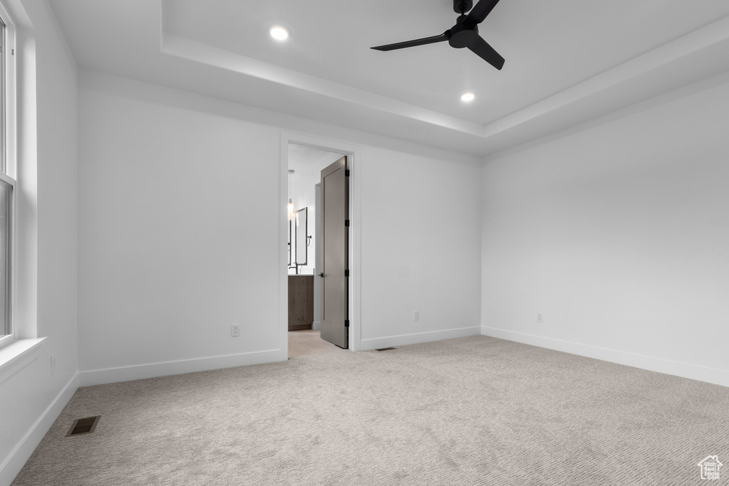 Spare room with a raised ceiling, a ceiling fan, light colored carpet, and recessed lighting