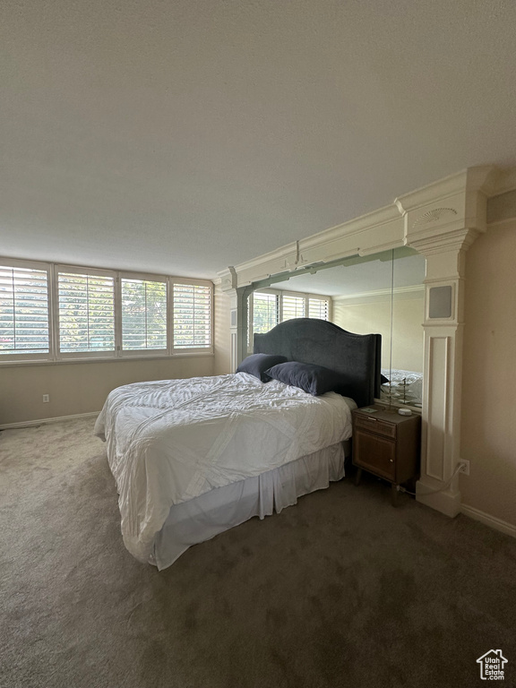 Carpeted bedroom with baseboards and decorative columns