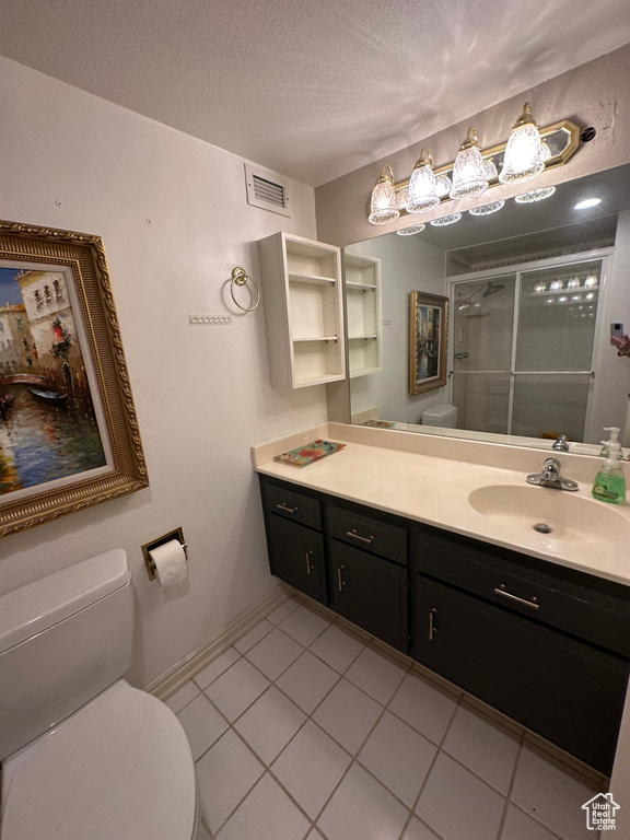Bathroom with vanity, a shower stall, tile patterned flooring, and a textured ceiling