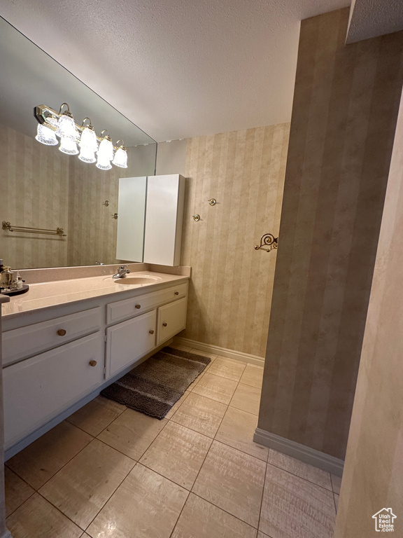 Bathroom with wallpapered walls, vanity, a textured ceiling, and tile patterned floors
