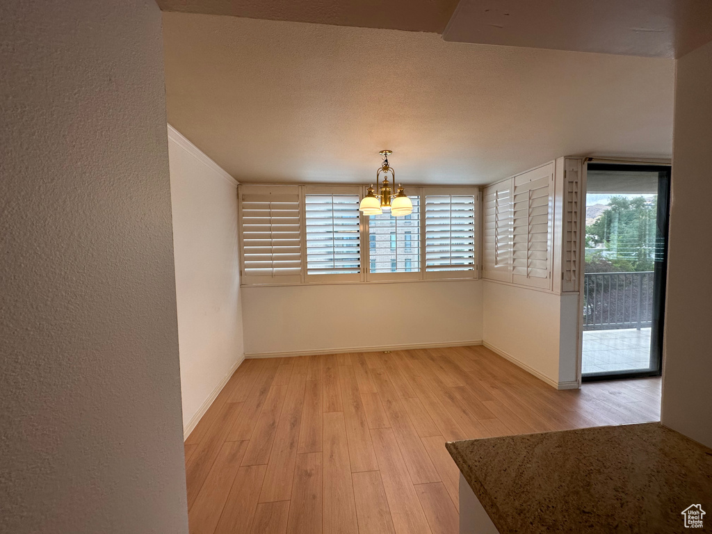 Unfurnished dining area with light wood finished floors and a chandelier