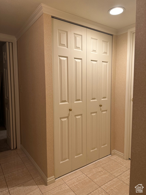Hallway with crown molding and light tile patterned floors
