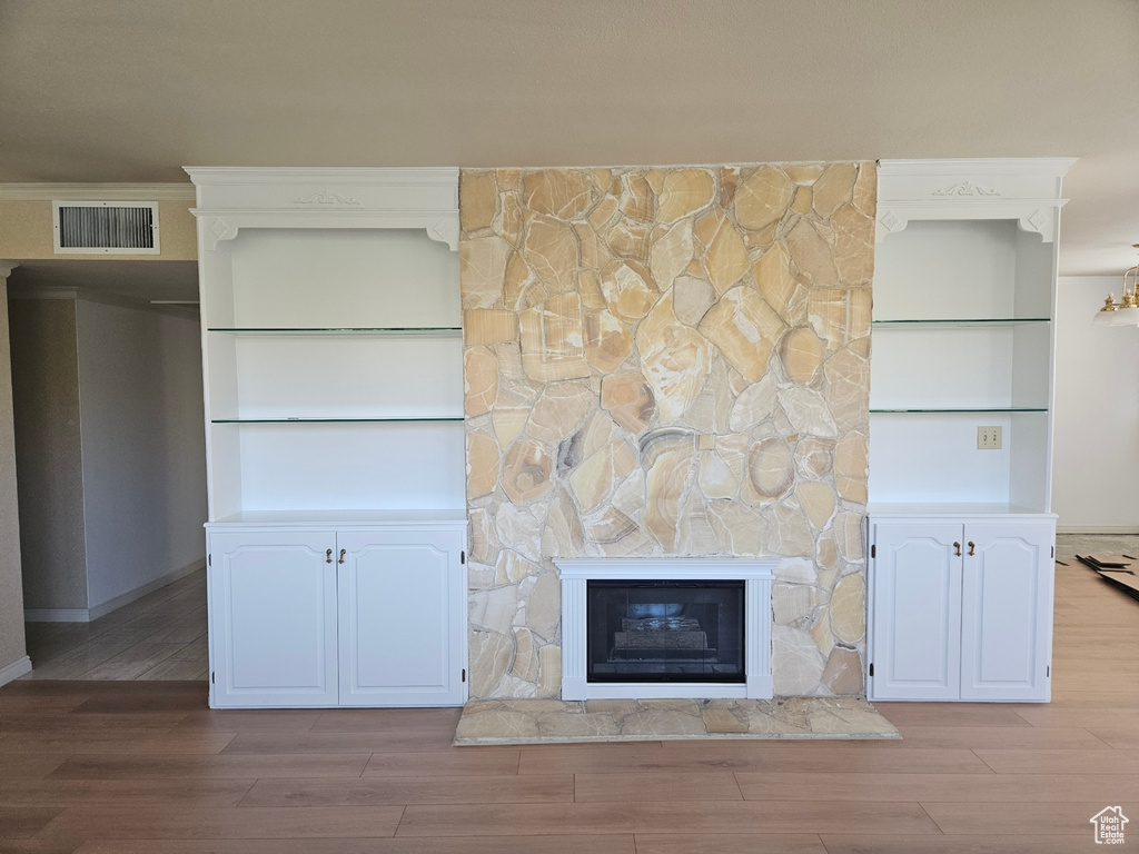 Unfurnished living room featuring wood finished floors and a stone fireplace