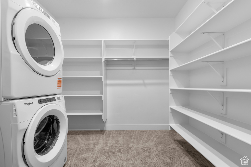 Washroom featuring stacked washer / drying machine and carpet floors