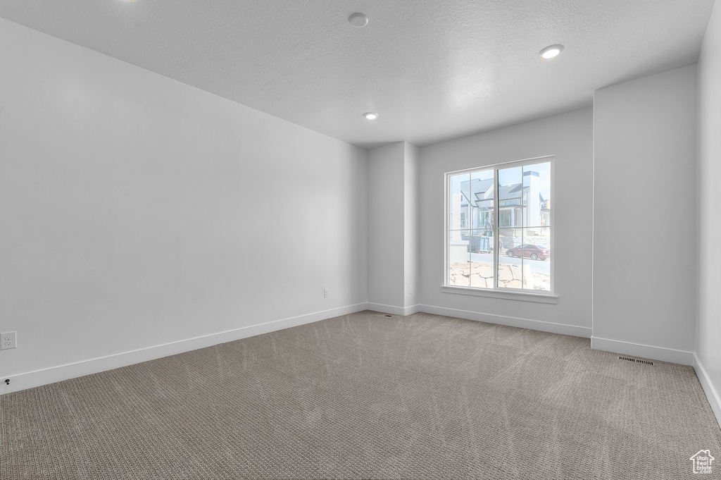 Empty room featuring light carpet, recessed lighting, and a textured ceiling