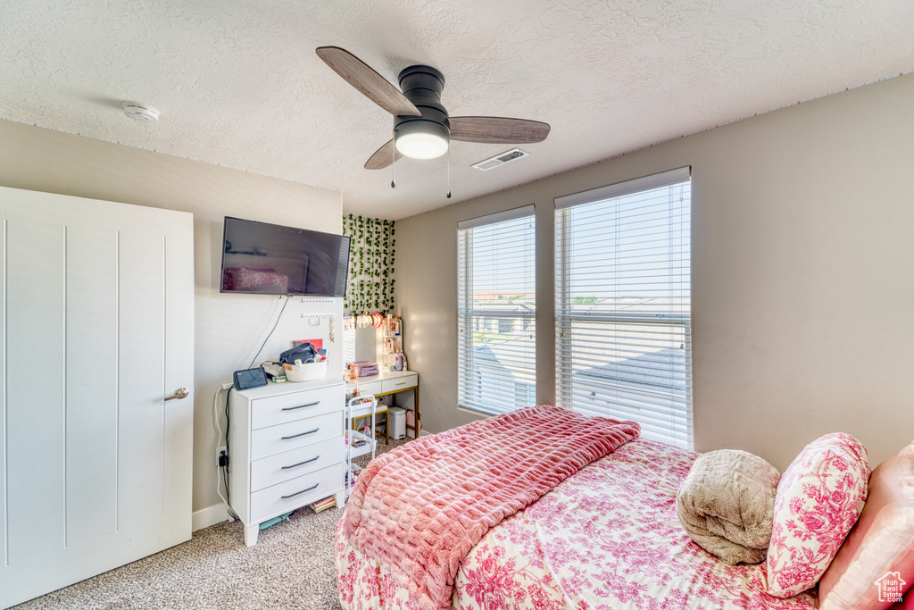 Bedroom featuring light carpet, a textured ceiling, and a ceiling fan