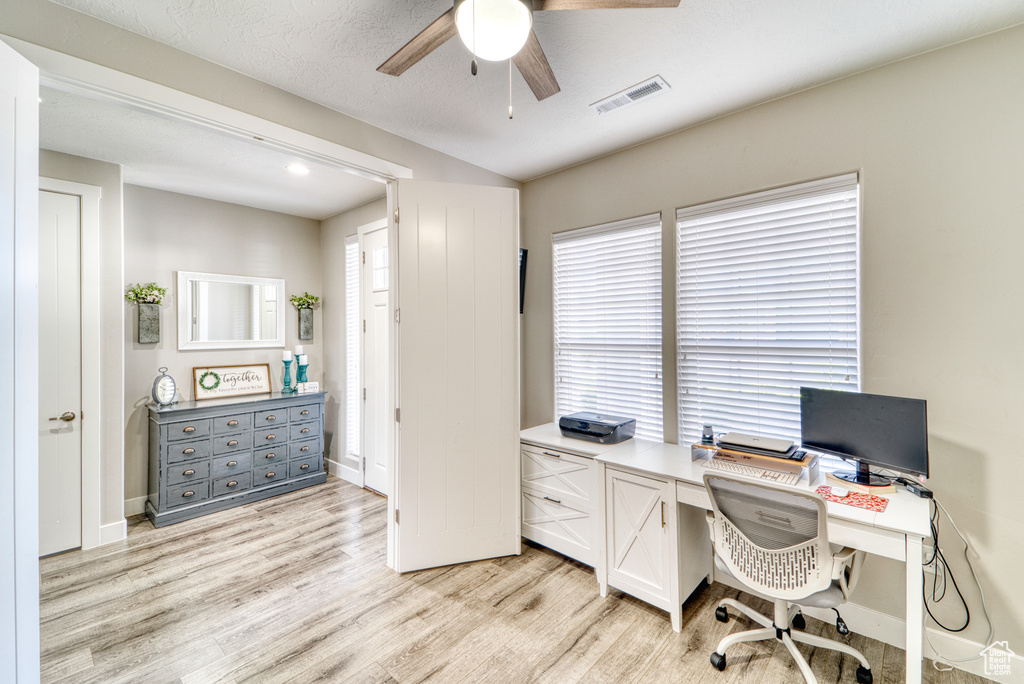 Home office with ceiling fan, light wood-style floors, and healthy amount of natural light