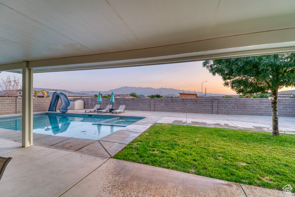 View of pool with a water slide, a patio, a fenced backyard, and a pool with connected hot tub
