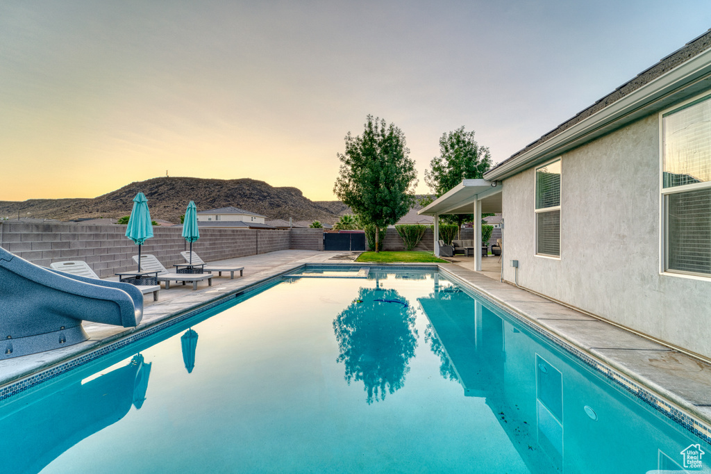 View of swimming pool with a mountain view, a fenced backyard, a water slide, and a patio area