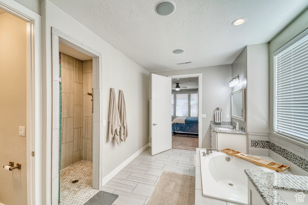 Ensuite bathroom featuring vanity, a bath, tiled shower, a ceiling fan, and a textured ceiling