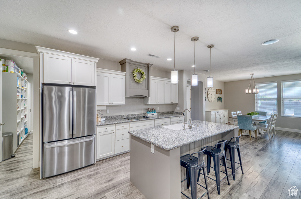 Kitchen featuring freestanding refrigerator, black electric cooktop, light wood finished floors, white cabinetry, and recessed lighting