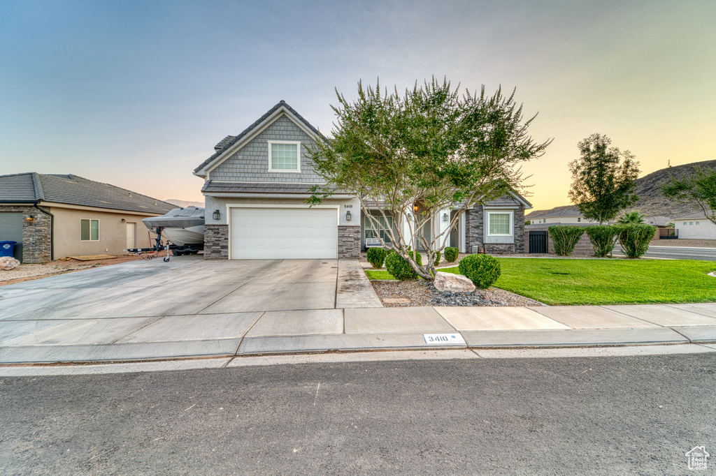 View of front of home featuring stone siding, concrete driveway, a front yard, and a garage
