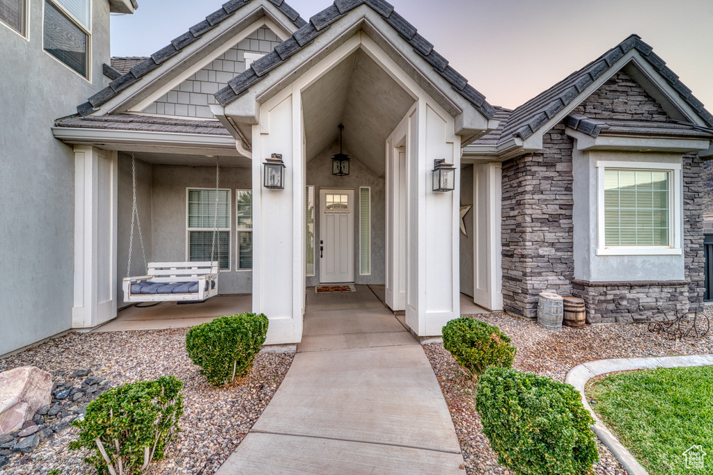 Property entrance featuring stone siding, stucco siding, and covered porch