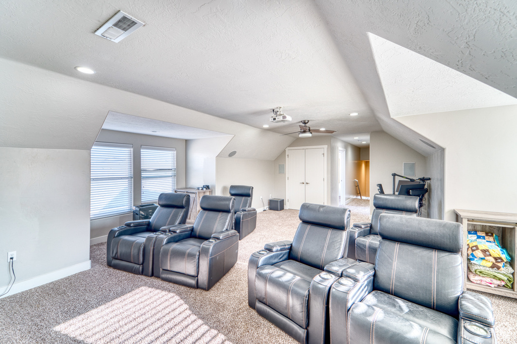 Carpeted home theater featuring vaulted ceiling, a textured ceiling, ceiling fan, and recessed lighting