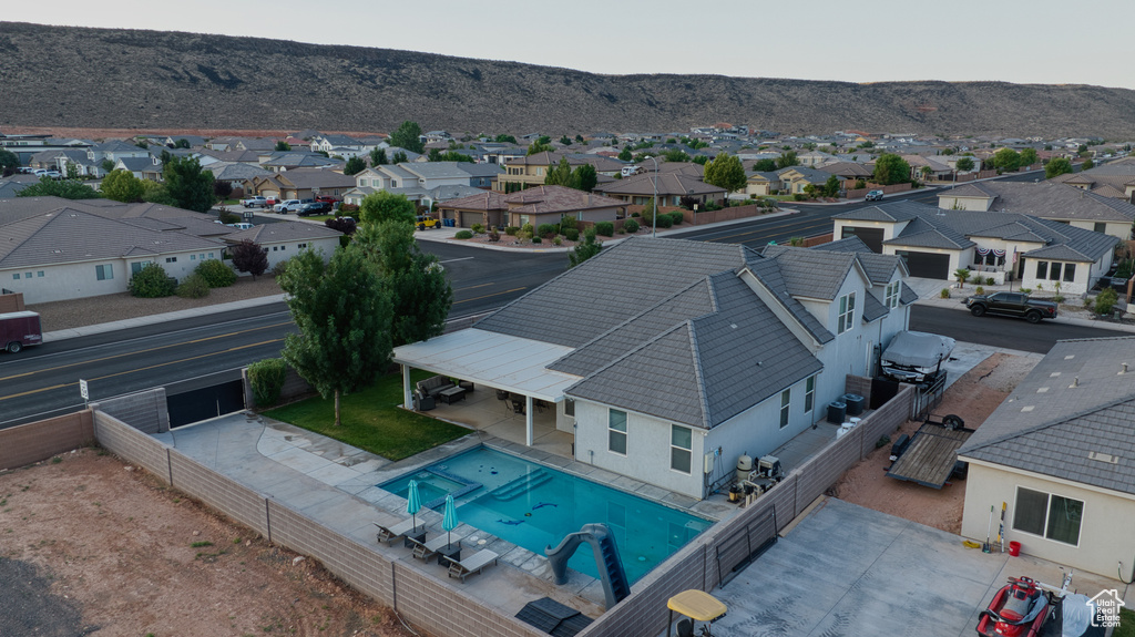 Aerial view of residential area featuring a mountain backdrop and a pool