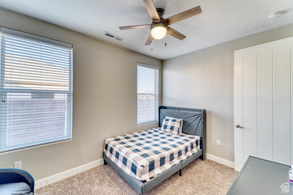 Bedroom featuring light colored carpet, ceiling fan, and a textured ceiling