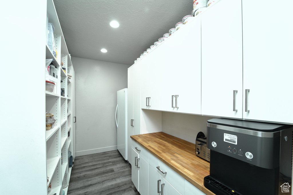 Kitchen with wood counters, wood finished floors, white cabinets, freestanding refrigerator, and open shelves