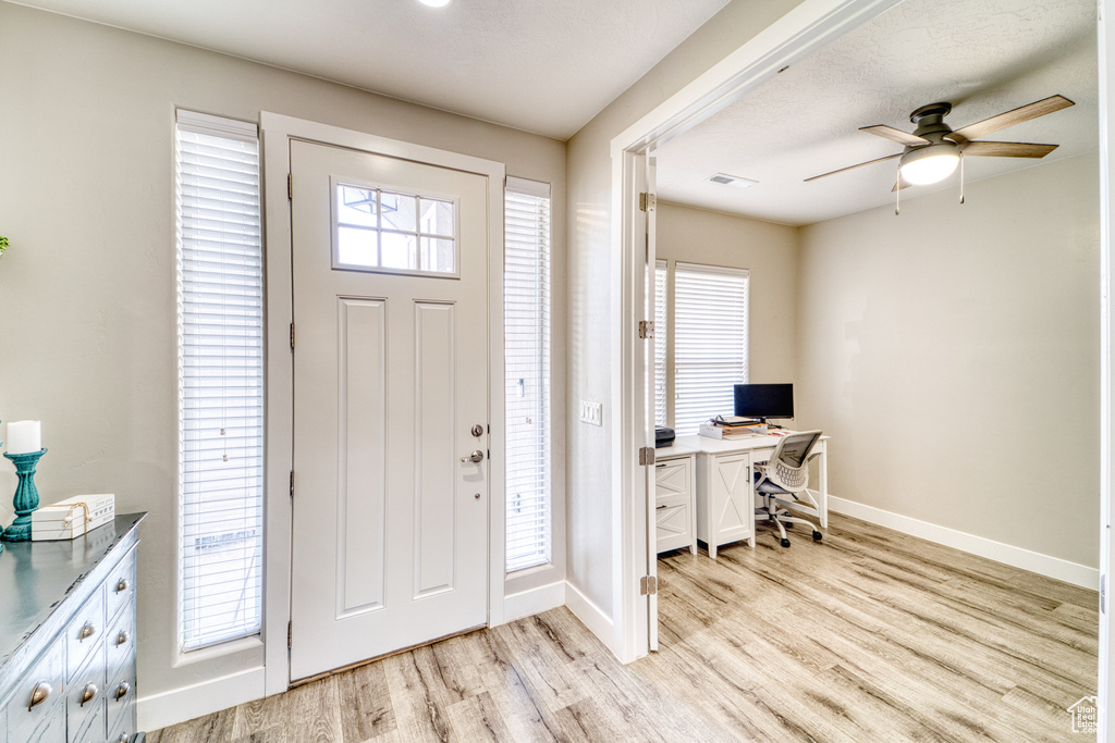 Foyer entrance with light wood-type flooring, ceiling fan, and healthy amount of natural light