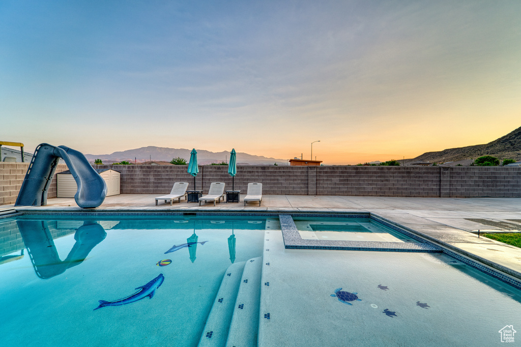 View of pool featuring a water slide, a mountain view, a patio area, and a pool with connected hot tub
