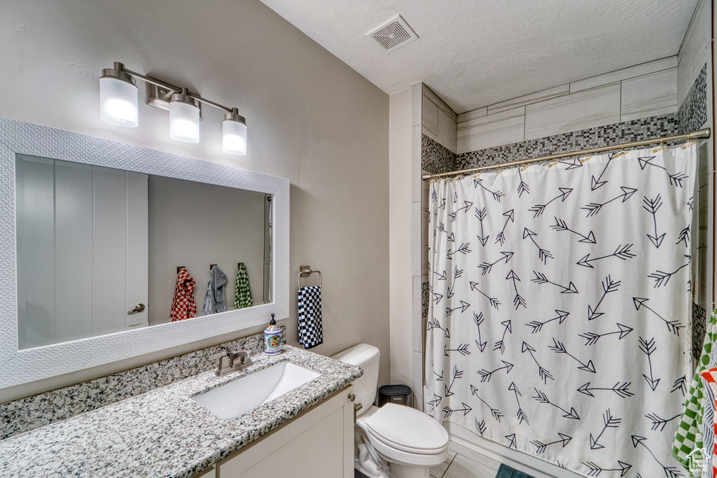 Full bath with vanity, curtained shower, and a textured ceiling