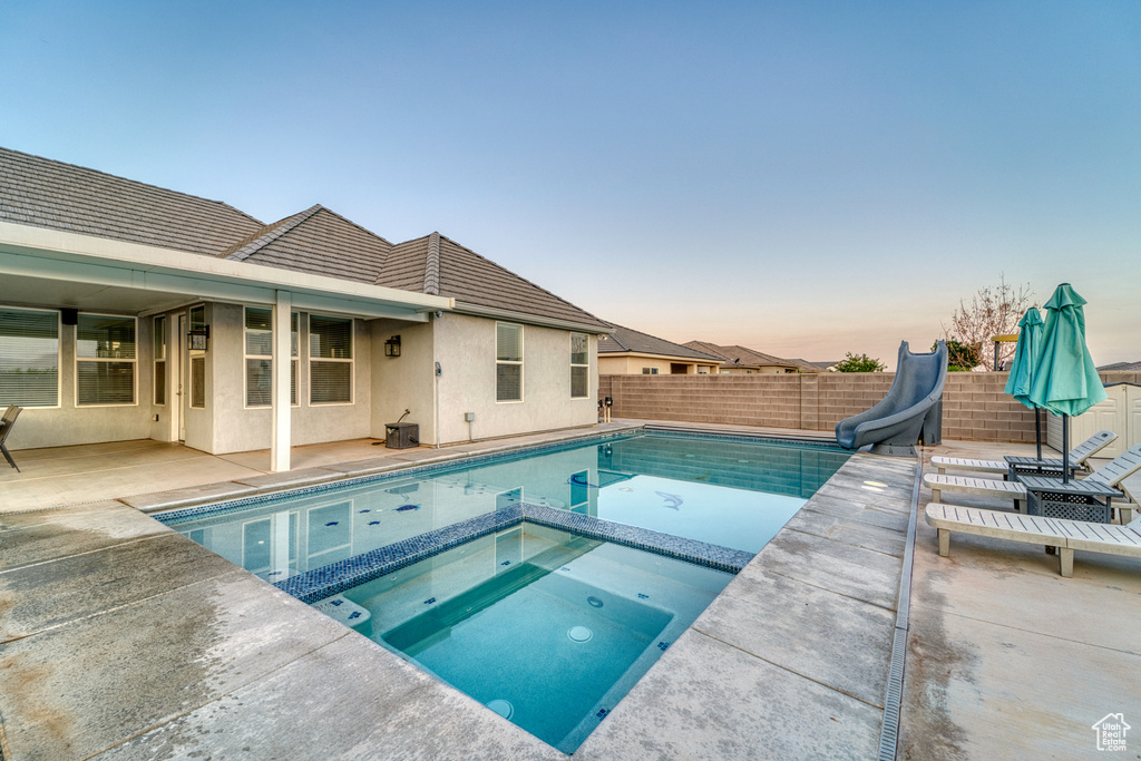 View of swimming pool with a water slide, a patio, a fenced backyard, and a pool with connected hot tub