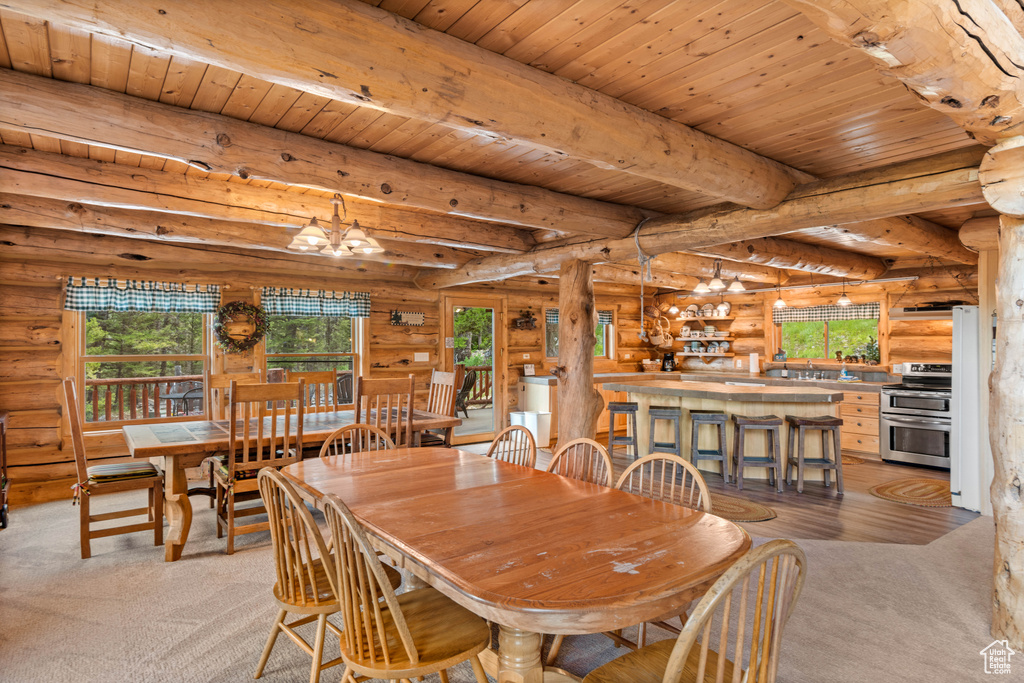 Dining room featuring log walls, light colored carpet, a wooden ceiling with exposed beams, a chandelier, and healthy amount of natural light