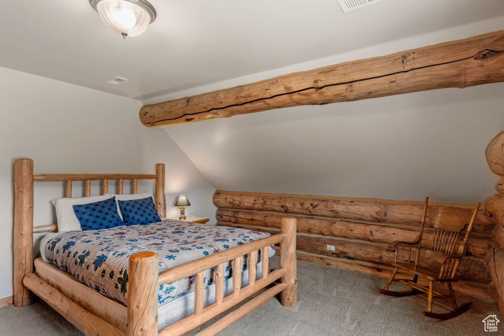 Carpeted bedroom featuring rustic walls