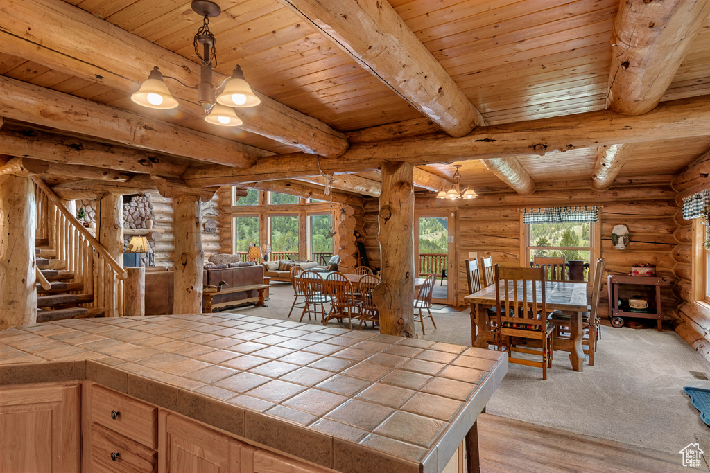 Dining space featuring rustic walls, a wooden ceiling with exposed beams, a chandelier, stairs, and light wood finished floors