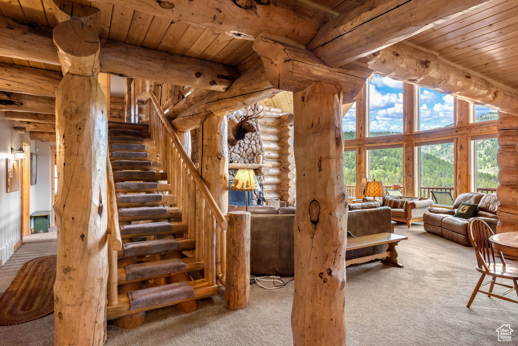 Staircase featuring rustic walls, a wood ceiling with exposed beams, and carpet