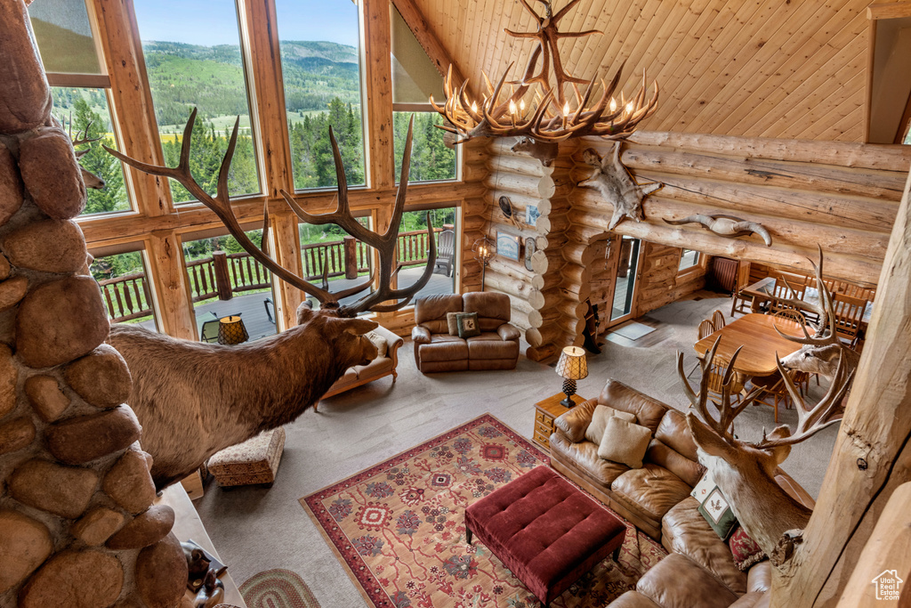 Living room with log walls, high vaulted ceiling, a chandelier, carpet, and a mountain view