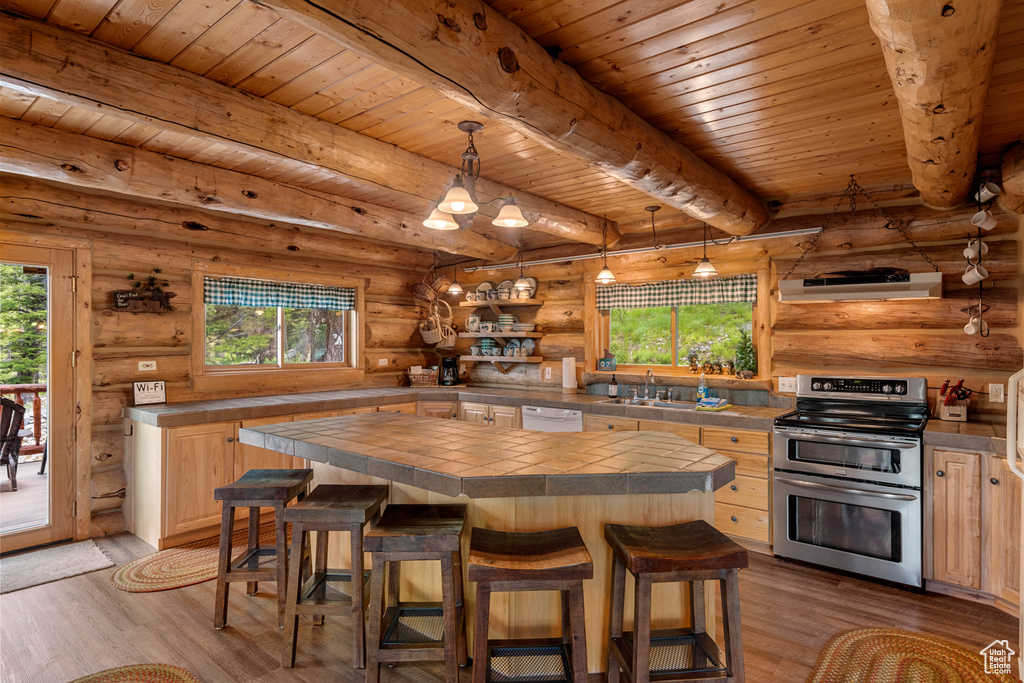 Kitchen featuring double oven range, healthy amount of natural light, tile counters, a wood ceiling with exposed beams, and log walls