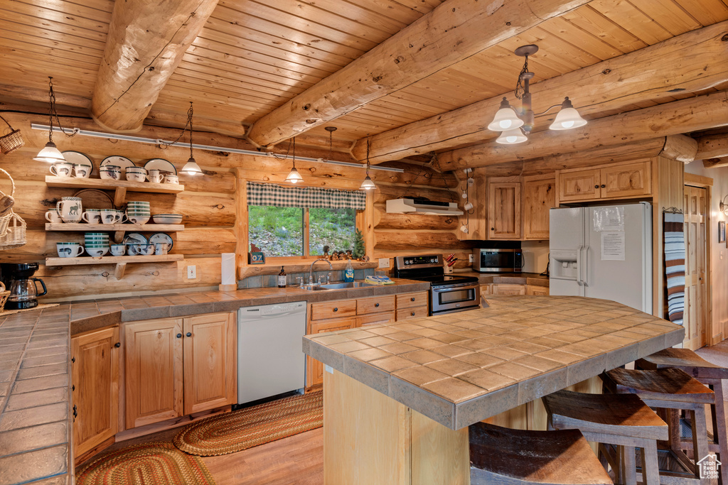 Kitchen with stainless steel appliances, log walls, tile counters, a wooden ceiling with exposed beams, and light wood-style floors