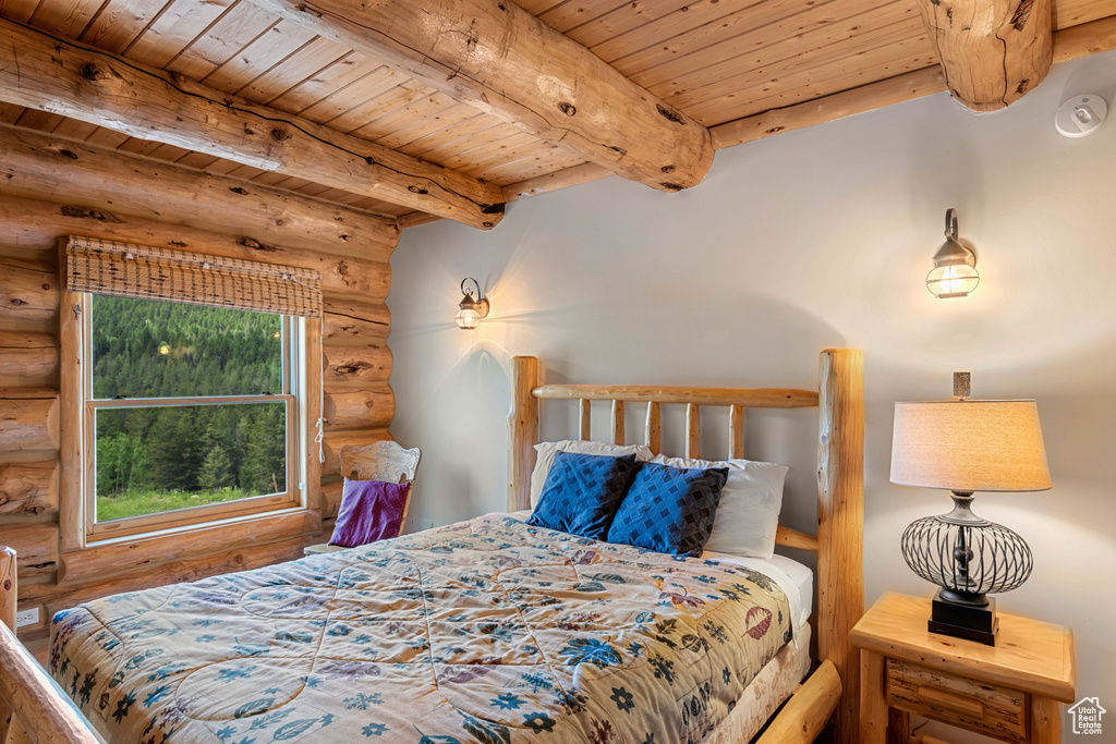 Bedroom with log walls, a wood ceiling with exposed beams, and wood finished floors