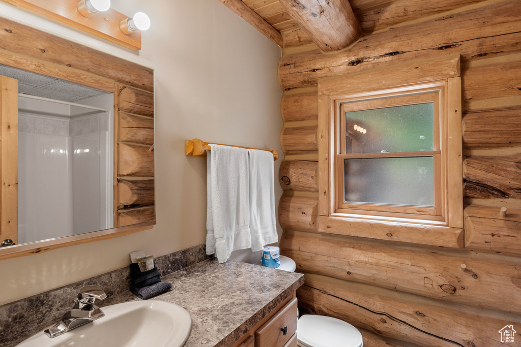 Bathroom featuring log walls, a wooden ceiling with exposed beams, a shower, and vanity