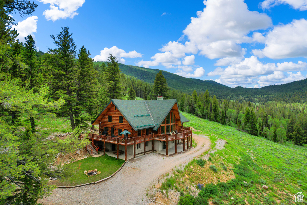 Aerial view of property and surrounding area featuring a heavily wooded area and mountains