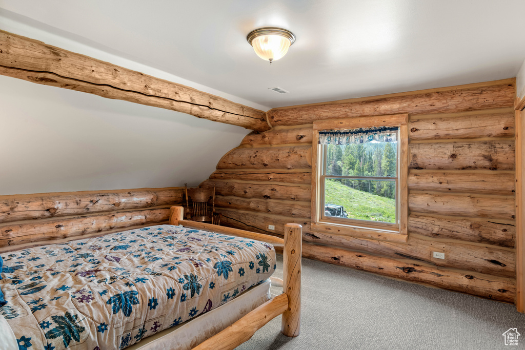 Carpeted bedroom featuring log walls