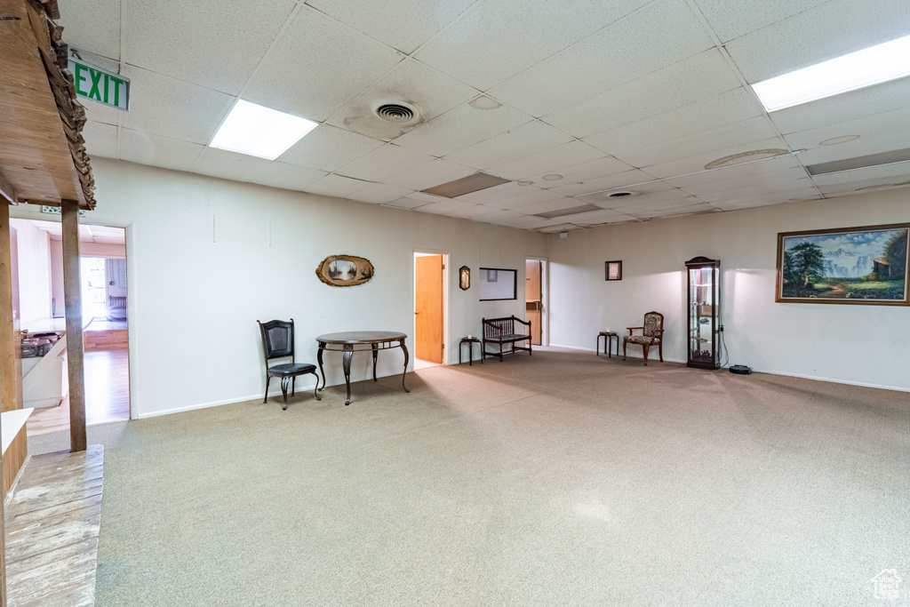 Living area featuring a paneled ceiling and carpet floors