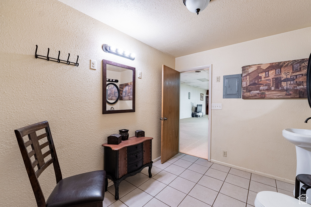 Hall with light tile patterned floors, electric panel, a textured ceiling, and a textured wall
