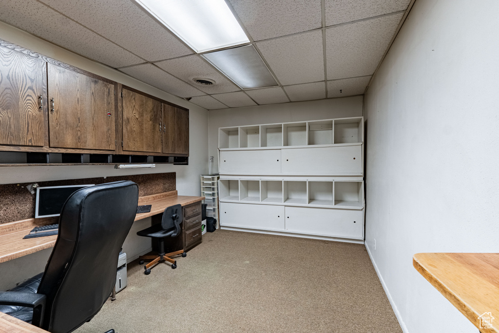 Home office with light colored carpet and a drop ceiling
