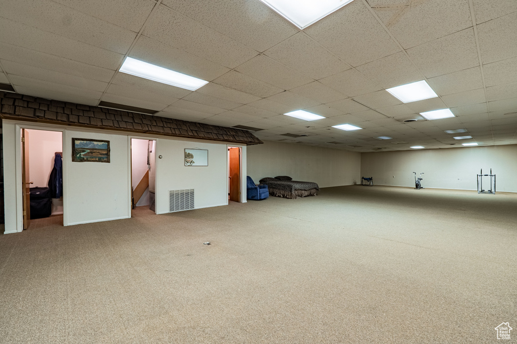 Carpeted empty room with stairs and a paneled ceiling