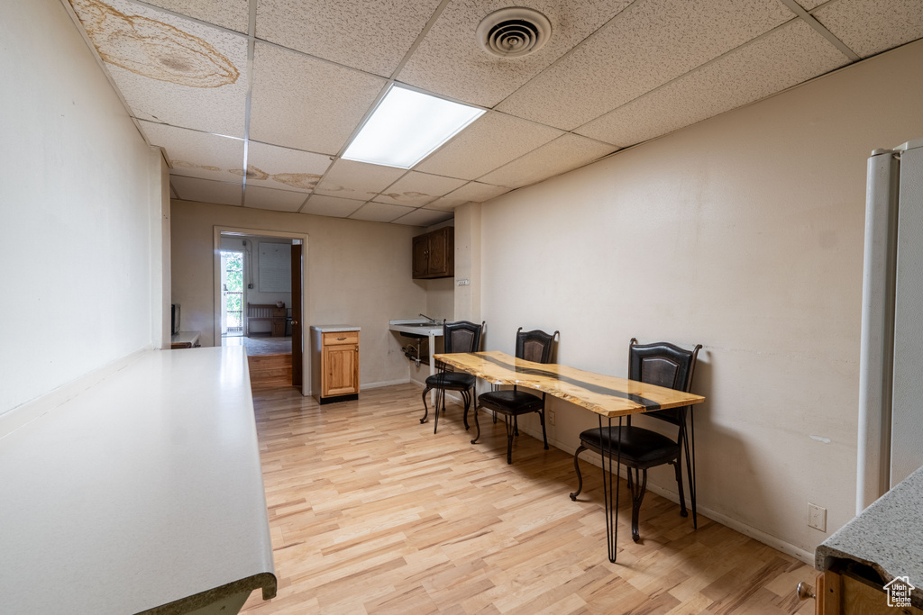 Home office with a paneled ceiling and light wood finished floors