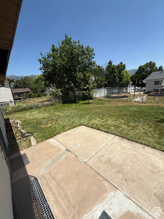 Fenced backyard featuring a patio area, a trampoline, and a mountain view