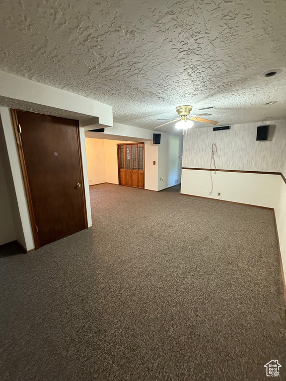 Finished basement with a ceiling fan and a textured ceiling
