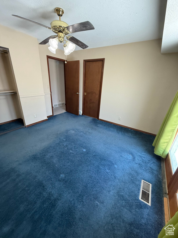 Unfurnished bedroom featuring a ceiling fan, a textured ceiling, carpet, and multiple closets