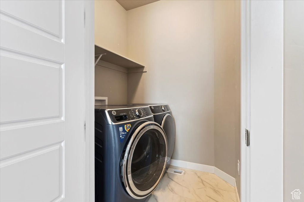 Washroom with independent washer and dryer and marble look tile flooring
